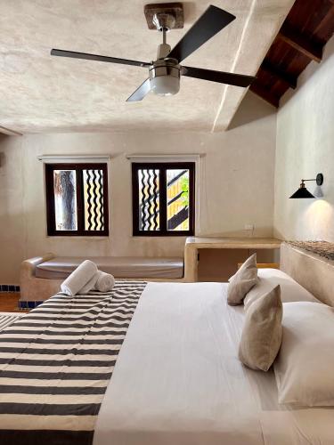 a bedroom with a large white bed with a ceiling fan at La Conchita Tulum in Tulum