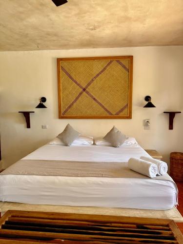 a bedroom with a white bed with a picture on the wall at La Conchita Tulum in Tulum