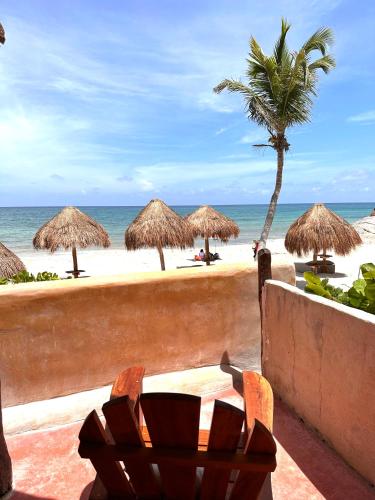 a beach with straw umbrellas and a table and chairs at La Conchita Tulum in Tulum