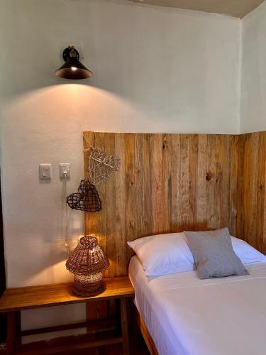 a bedroom with a bed with a wooden headboard and a lamp at La Conchita Tulum in Tulum