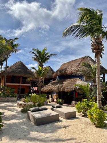 a resort with palm trees and beds in the sand at La Conchita Tulum in Tulum