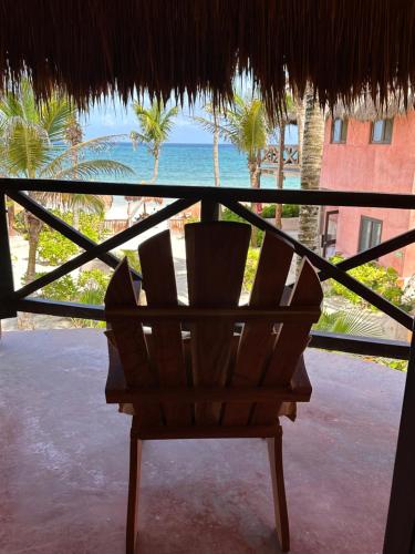 a chair in a thatched room with a view of the ocean at La Conchita Tulum in Tulum