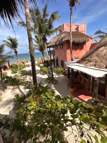 a building on the beach with palm trees and the ocean at La Conchita Tulum in Tulum