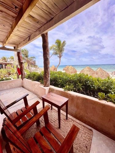 a porch with chairs and a table and the beach at La Conchita Tulum in Tulum