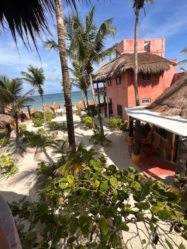 a building on the beach with palm trees and the ocean at La Conchita Tulum in Tulum