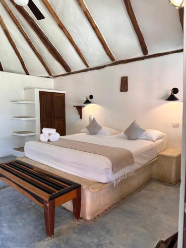 a bedroom with a bed and a bench in it at La Conchita Tulum in Tulum