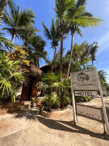 a sign in front of a hotel with palm trees at La Conchita Tulum in Tulum