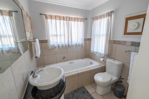 uma casa de banho com uma banheira, um WC e um lavatório. em Fairways Apartment Mossel Bay Golf Estate em Mossel Bay
