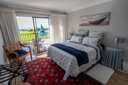 a bedroom with a bed and a large window at Fairways Apartment Mossel Bay Golf Estate in Mossel Bay