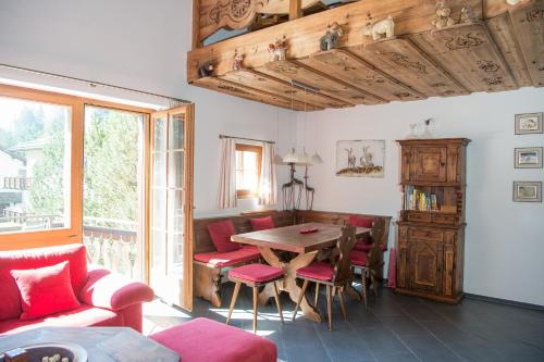 a living room with a wooden table and red chairs at Holiday flat with Jacuzzi for 6 persons-Lenzerheide in Lenzerheide