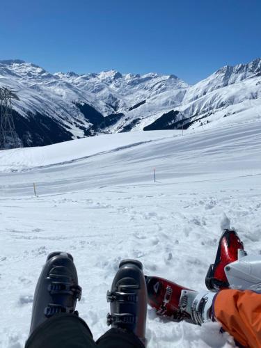 a person sitting in the snow with their feet in the snow at Mountain Getaway Sedrun in Rueras