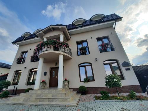 a white house with a balcony and stairs at AristoCat Hotels Rasnov in Râşnov