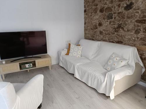ein Wohnzimmer mit einem weißen Sofa und einem Flachbild-TV in der Unterkunft Casa Remes in Sagunt