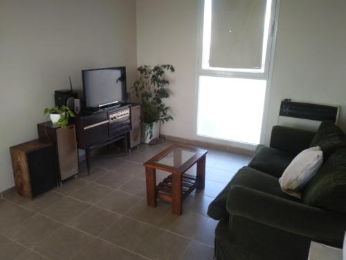 sala de estar con sofá y TV en Departamento temporario Puerto Madryn en Puerto Madryn