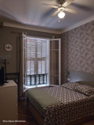 - une chambre avec un lit, un ventilateur de plafond et une fenêtre dans l'établissement Central Station apartment, à Nice