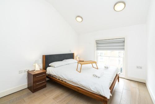 een slaapkamer met een bed met een nachtkastje en een raam bij Cozy 2 Bedroom / Earls Court / Balcony in Londen