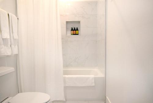 e bagno con tenda da doccia bianca, vasca e servizi igienici. di Hollywood Hills Hotel a Los Angeles