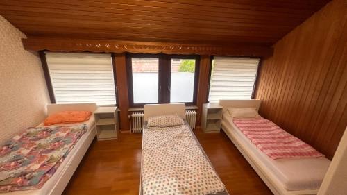 a room with two beds and two windows at Pension Asel in Wörth am Rhein