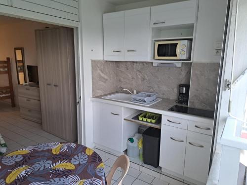 a kitchen with white cabinets and a microwave at Studio cosy les pieds dans l'eau à l'autre bord in Le Moule
