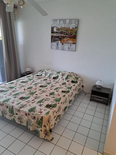 a bedroom with a bed with a floral comforter at Studio cosy les pieds dans l'eau à l'autre bord in Le Moule