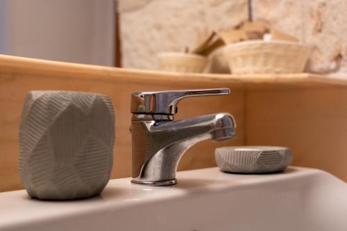 ein Waschbecken mit einem Wasserhahn und einem Papierhandtuch-Halter in der Unterkunft Trullo vacanze di Cummà Rosa in Alberobello
