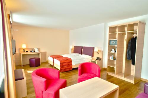 a hotel room with a bed and two chairs at Hotel Coop Tagungszentrum & Hotelpark im Grünen in Muttenz