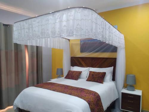a bedroom with a large white bed with a canopy at KAWETA COTTAGE in Yadinga