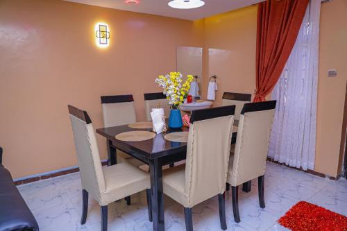 - une salle à manger avec une table, des chaises et des fleurs dans l'établissement Milimani Apartment Comfy Homestay, à Nakuru