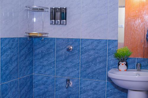 La salle de bains est pourvue de carrelage bleu, de toilettes et d'un lavabo. dans l'établissement Milimani Apartment Comfy Homestay, à Nakuru