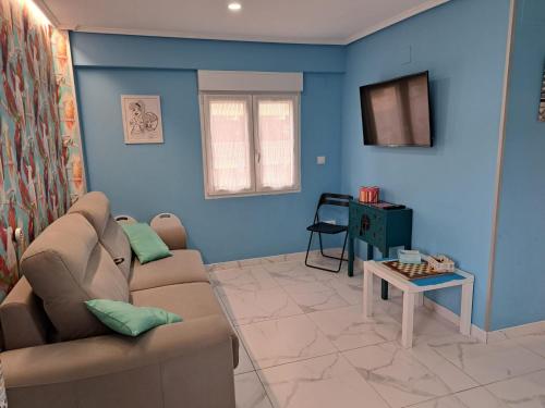 un soggiorno con pareti blu, divano e tavolo di Apartamento Zona Playa y centro Ciudad a Santander