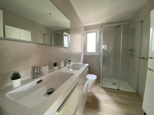 a white bathroom with a sink and a shower at Fantastica casa con piscina a 5 min a pie del mar - Sorramar in Gavà