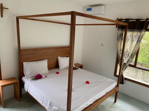 Un dormitorio con una cama con dosel y flores. en Blue Villa Zanzibar en Pwani Mchangani