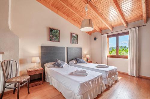 a bedroom with two beds and a large window at Sa Sort in Alaró