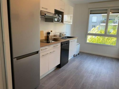 a kitchen with a refrigerator and a counter top at Appartement cosy 80m2 au pied du tram de Bordeaux in Eysines