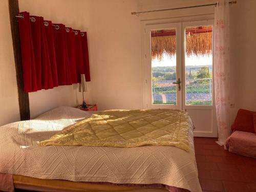 a bedroom with a bed and a window with red curtains at Métairie de Moutiques in Cazaubon
