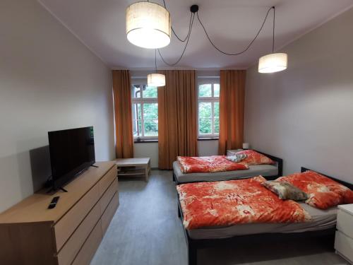 a bedroom with two beds and a flat screen tv at Apartament nr 2 w Starym Nadleśnictwie in Kościerzyna