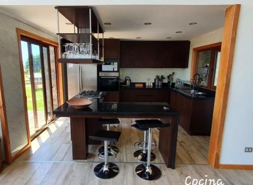 a kitchen with a large island with bar stools at Casa Country Pucon in Villarrica