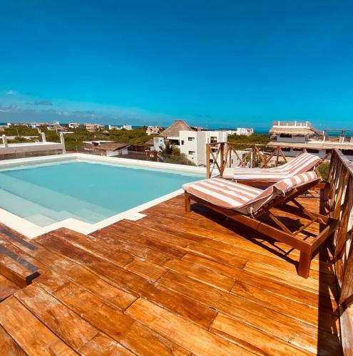 eine Terrasse mit einem Stuhl und einem Pool in der Unterkunft Sunsteps casa holbox in Holbox