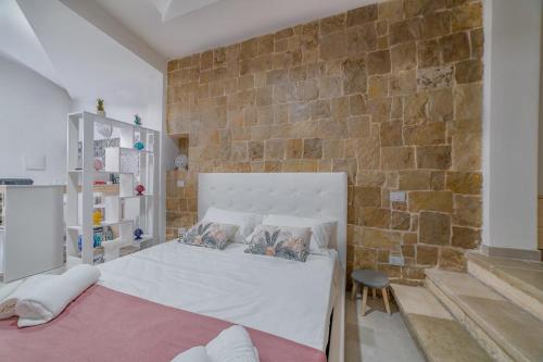 una camera con un letto bianco e un muro di mattoni di Dimora Dante a Ceglie Messapica