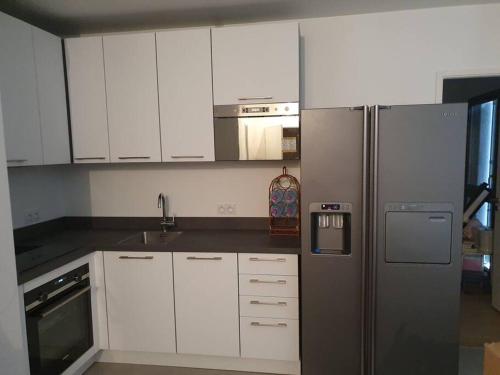uma cozinha com armários brancos e um frigorífico de aço inoxidável em Appartement avec Balcon Pontoise PARIS Nord-ouest em Pontoise