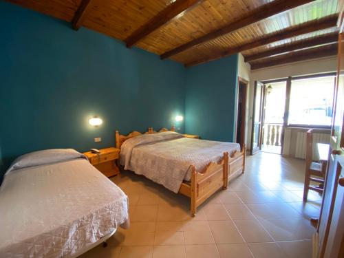 a bedroom with two beds and a large window at Albergo Nazionale in San Giacomo