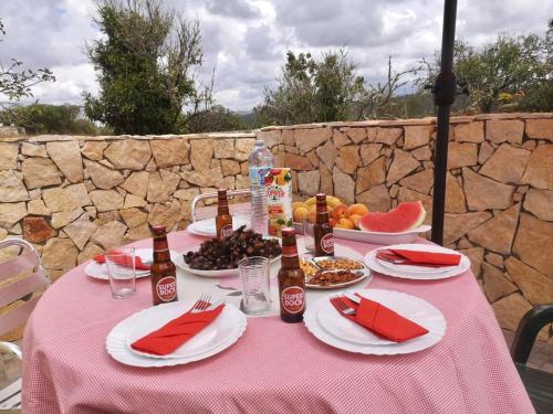 una mesa con un mantel rosa con comida y bebida en Casa Manuel J. J. M -Alfambras, Aljezur - Quiet Country House, en Aljezur