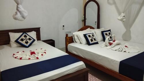 a bedroom with two beds with towels on them at Sigiri Dilu Villa in Sigiriya