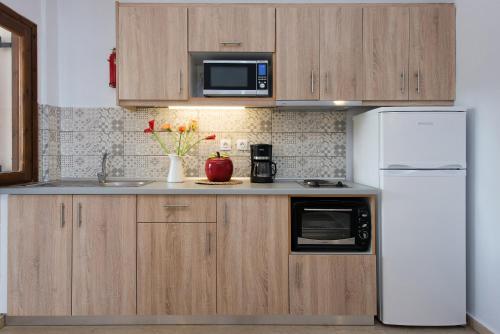 a kitchen with wooden cabinets and a white refrigerator at Hotel Barbati Sea View B&B in Barbati