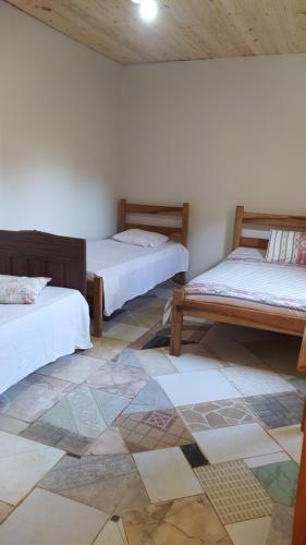 a room with two beds and a tiled floor at Casa Rustica Milho Verde in Milho Verde