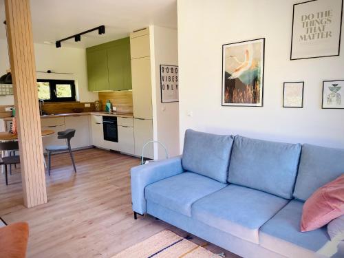 a living room with a blue couch and a kitchen at Rajska nowoczesna stodoła !!! in Dźwierzuty