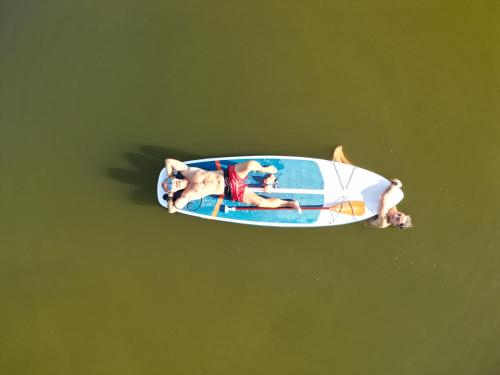 two people laying on a surfboard in the water at Rajska nowoczesna stodoła !!! in Dźwierzuty