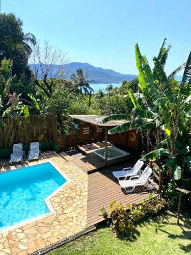 un patio trasero con piscina y terraza con sillas en Pousada Banana Verde, en Ilhabela