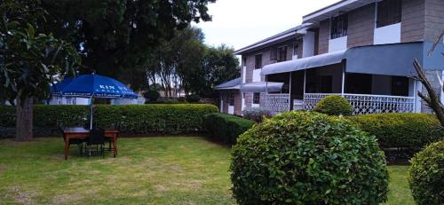 a table with an umbrella in a yard next to a building at Trans-Africa equator hotel in Eldoret