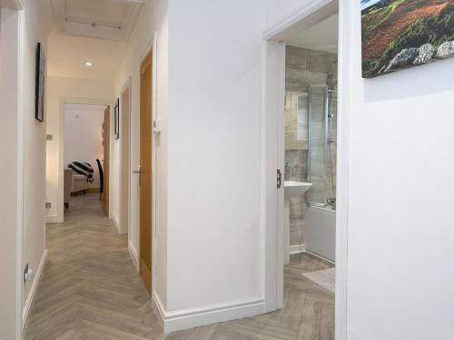 a hallway with white walls and wooden flooring at Pass the Keys Modern Coastal Home in Bull Bay in Amlwch